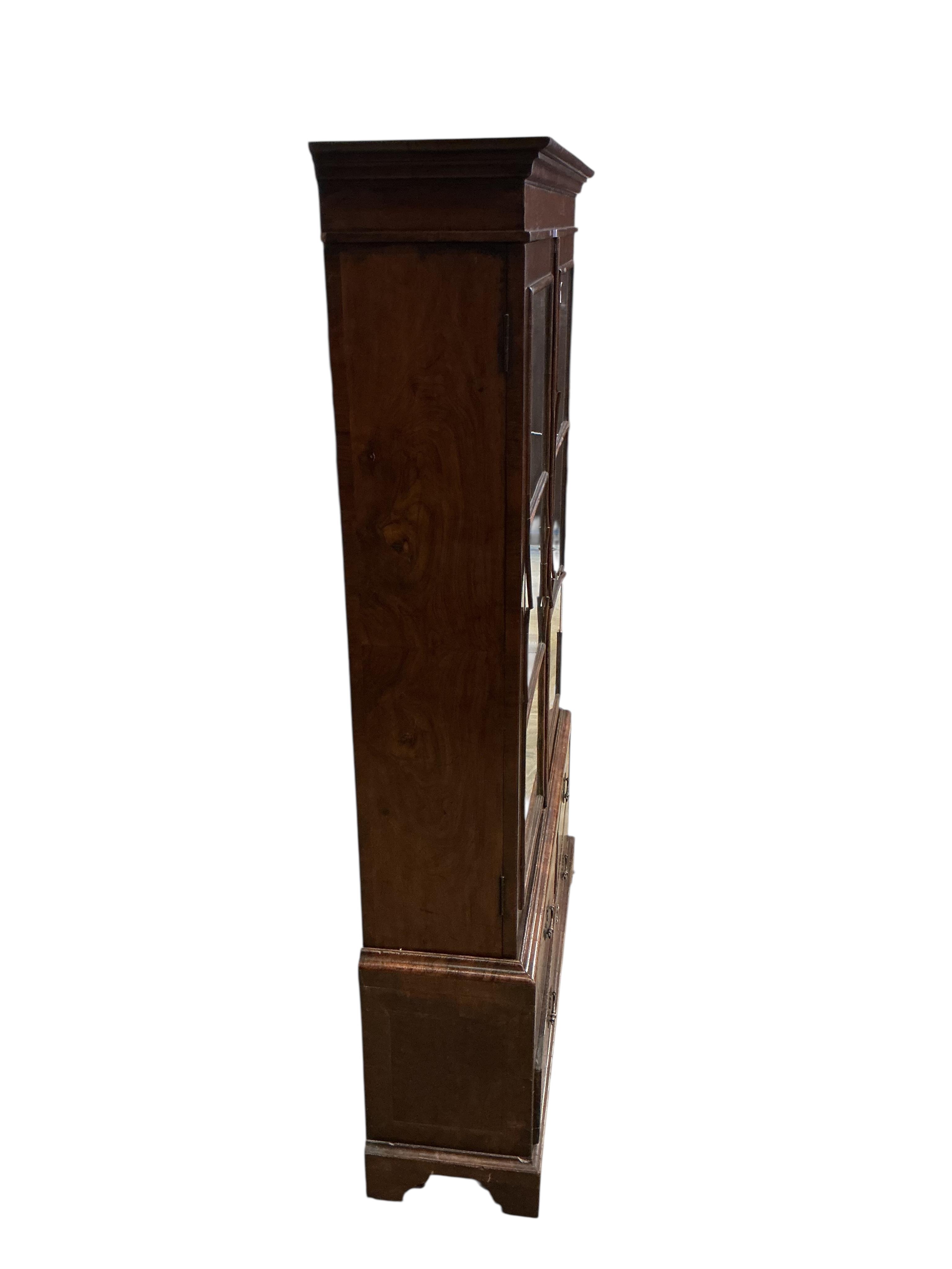 A Queen Anne Revival walnut two door bookcase, the base fitted with drawers, width 92cm, depth 27cm, height 154cm